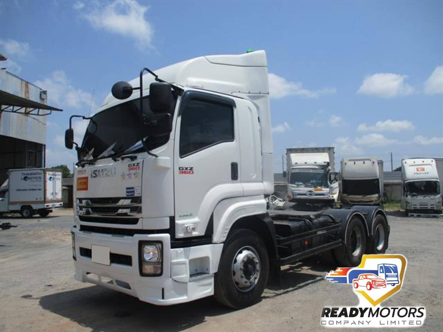 รถบรรทุก Isuzu GXZ 360 สีขาว จอดโชว์ในลาน พร้อมรถบรรทุกอื่นๆ ด้านหลัง